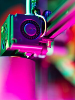 Close-up of a 3D printer in action under neon lighting, capturing vibrant colors and modern tech ambiance.